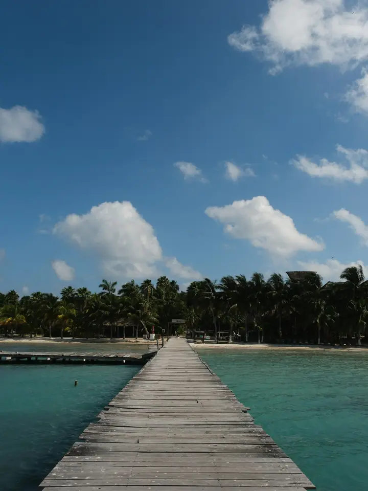 Muelle de madera sobre agua turquesa con la isla al fondo