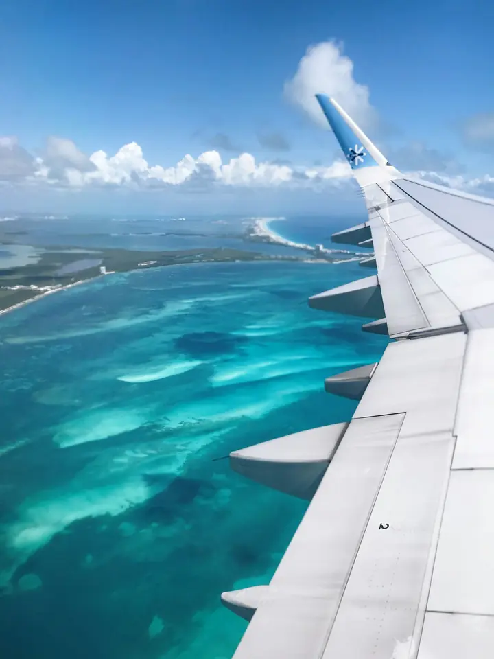 Ala de avión volando sobre el mar turquesa del Caribe